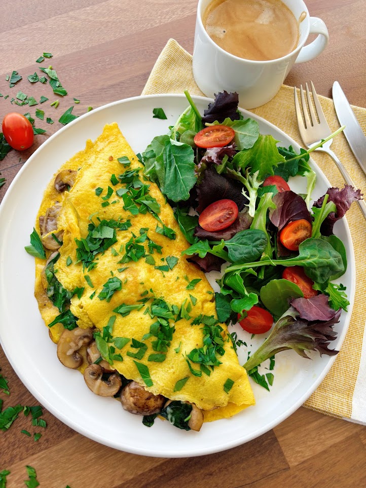 Savory spinach mushroom omelet filled with sautéed mushrooms, wilted spinach, and melted Gruyère in a nonstick skillet.