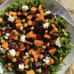 Roasted sweet potato beet and kale salad topped with crispy chickpeas pistachios feta and creamy tahini dressing