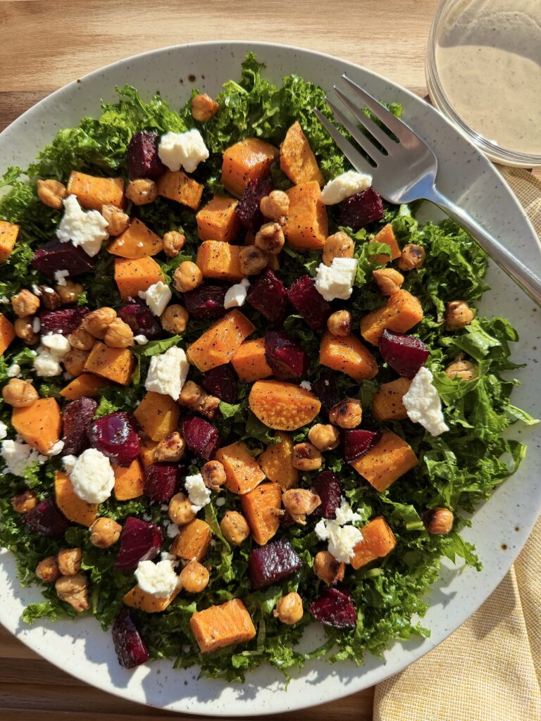 Roasted sweet potato beet and kale salad topped with crispy chickpeas pistachios feta and creamy tahini dressing