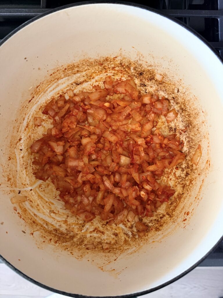 Onion, garlic, tomato paste, and Italian seasoning sautéing in a Dutch oven.