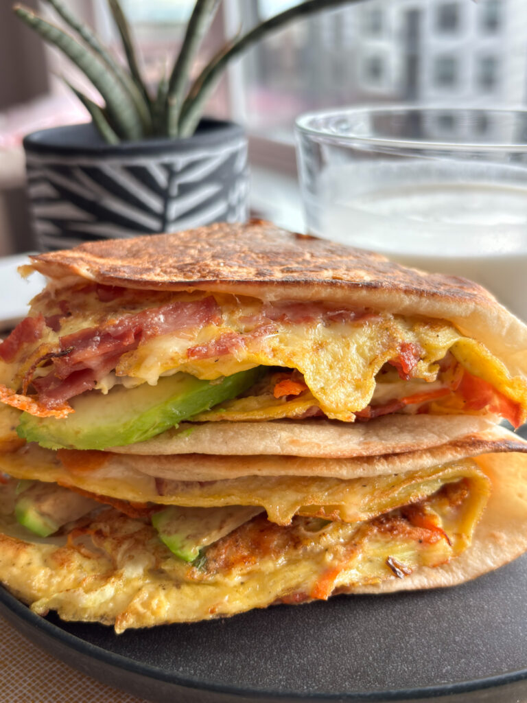 High-protein breakfast wrap with turkey bacon, eggs, cabbage, carrots, avocado, and melted cheese