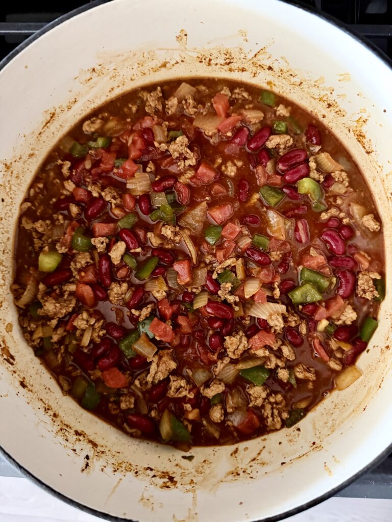 Tomatoes, kidney beans, and chicken broth added to ground chicken chili