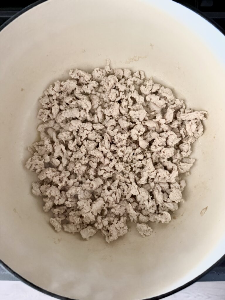 Ground chicken browning in a large pot for high-protein chicken chili
