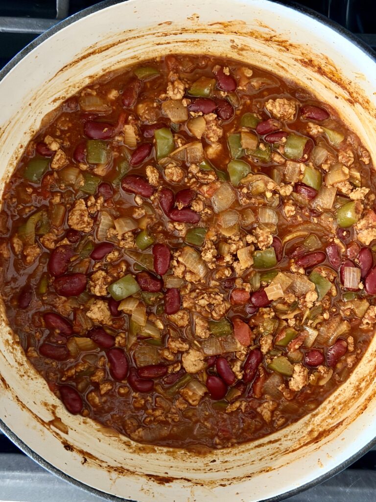 High-protein chicken chili with kidney beans simmering in a large pot