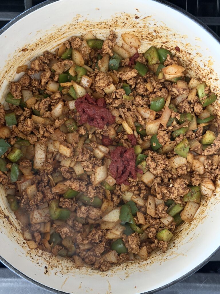 Tomato paste cooking with ground chicken and vegetables for chicken chili