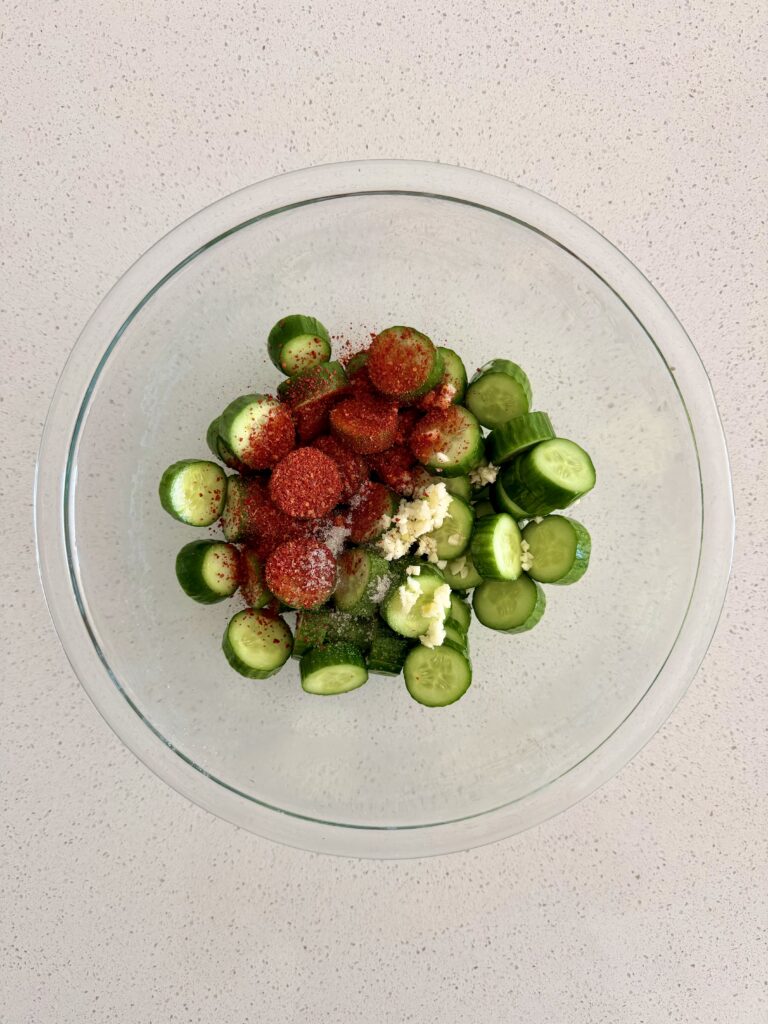 Cucumber slices topped with gochugaru, minced garlic, and sugar before tossing for oi muchim