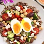 high-protein Mediterranean quinoa breakfast bowl with egg, chickpeas, feta, vegetables, olives, and tahini harissa dressing