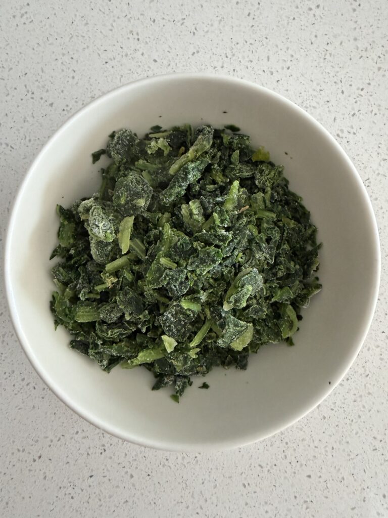 Frozen spinach in a bowl before cooking, used for a savory oatmeal breakfast bowl