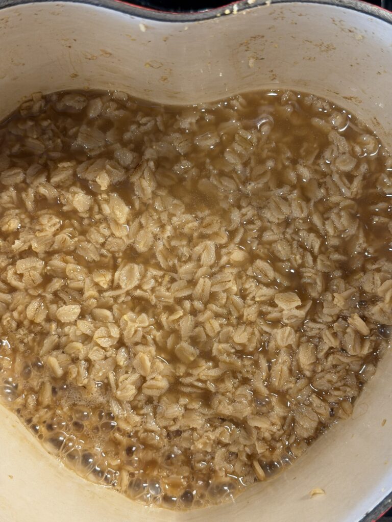 Rolled oats cooking in chicken broth in a pot, creating a savory oatmeal base