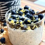Blueberry lemon cheesecake overnight oats in a jar topped with blueberries, chia seeds, and hemp hearts