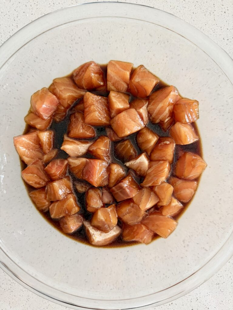 Cubed salmon marinating in a homemade teriyaki sauce in a bowl