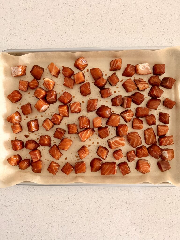 Cubed salmon arranged on a parchment-lined baking sheet, patted dry before broiling