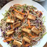 High-protein soba noodle salad with crispy tofu, red cabbage, snow peas, carrots, edamame, sesame dressing, and chili crisp.