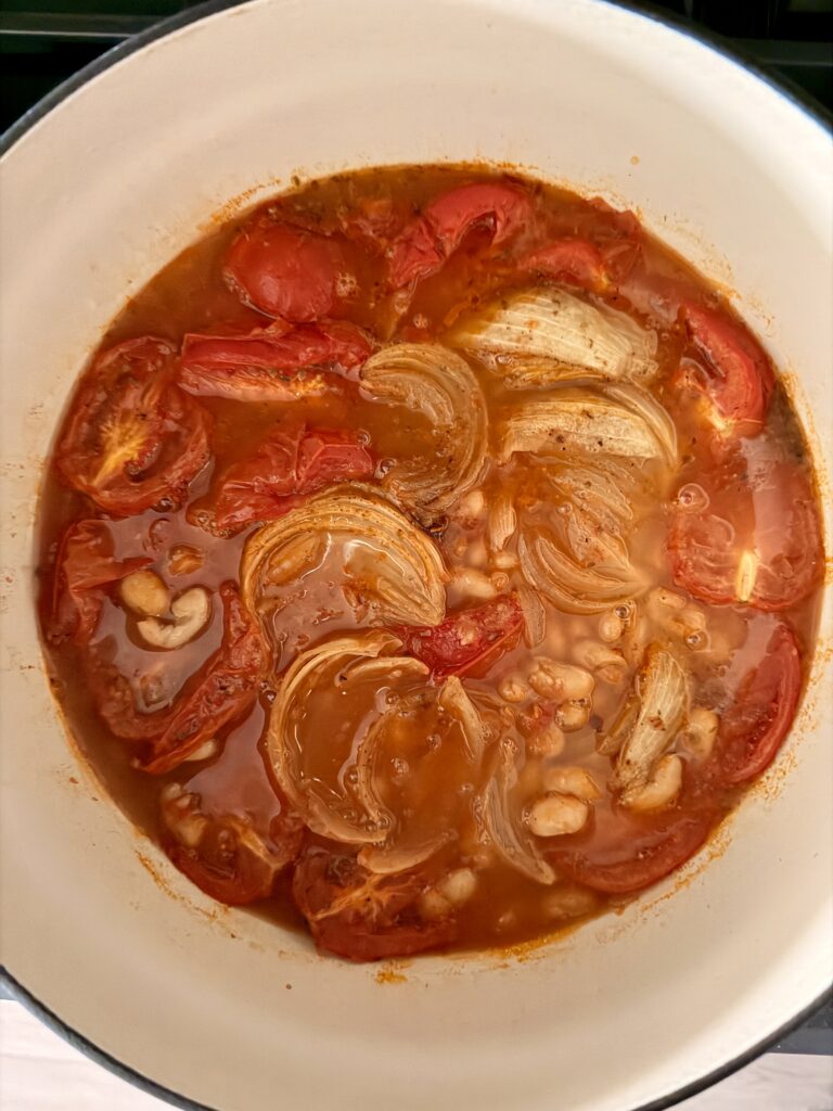 Roasted tomatoes, onion, and cannellini beans gently simmering in broth for white bean soup