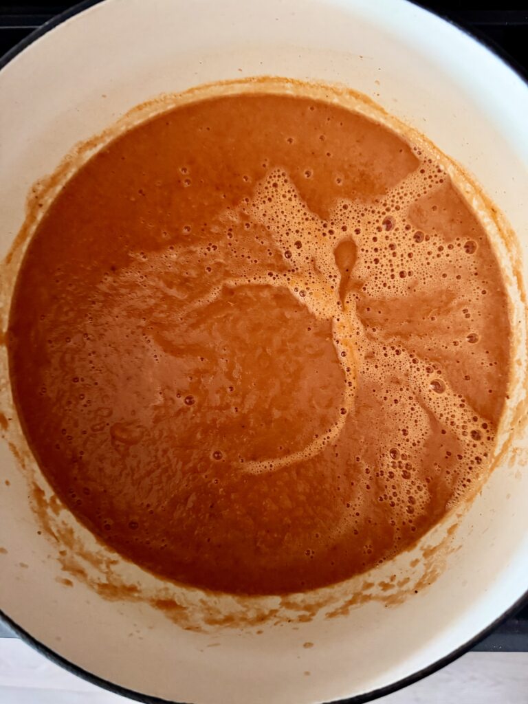 Smooth blended roasted tomato soup with a creamy texture in a pot