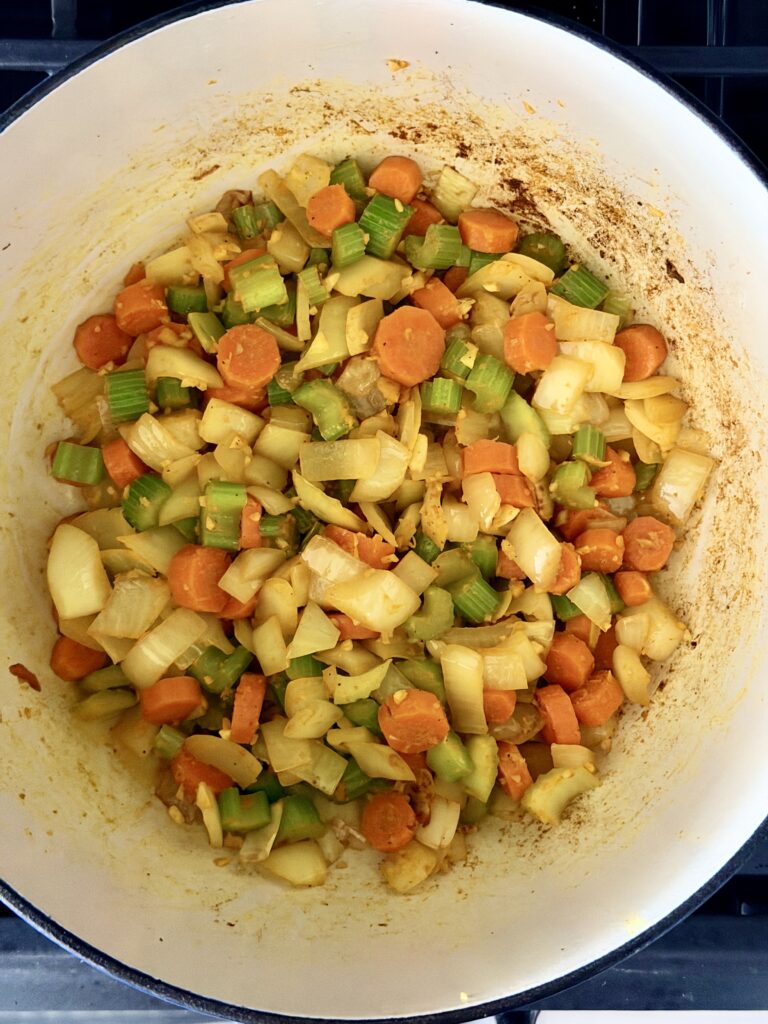 Sautéed vegetables coated in fresh ginger, garlic, and ground turmeric in a Dutch oven