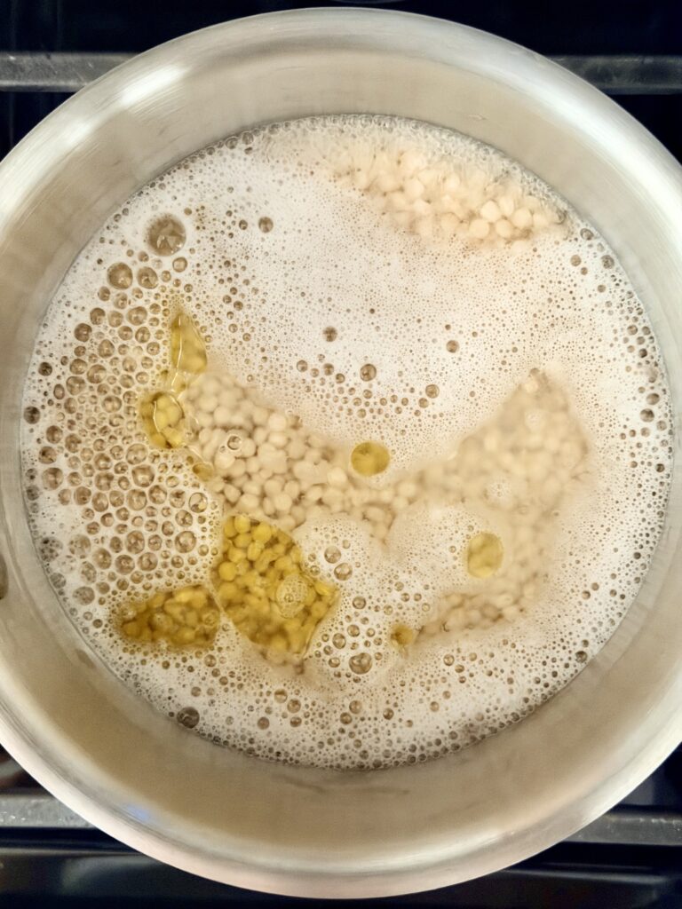 Pearl couscous boiling in a saucepan, cooked separately from the soup
