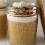 Close-up of a jar of pumpkin cheesecake chia pudding showing layers of pumpkin chia pudding, Greek yogurt, and graham cracker pecan topping