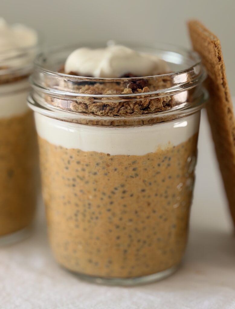 Close-up of a jar of pumpkin cheesecake chia pudding showing layers of pumpkin chia pudding, Greek yogurt, and graham cracker pecan topping
